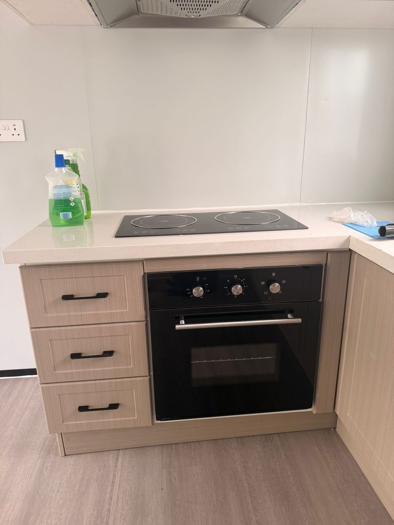 Compact fitted kitchen inside a ReadyNest modular home with integrated oven and induction hob