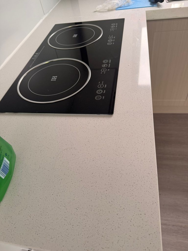 Durable quartz-style worktop and induction hob inside a modern modular home kitchen